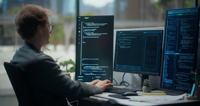  Using Working Computer. Male Developer in Modern Office Typing and Coding Mobile App Interface, Using Multiple Screens With Code, Ui PData Logic, Automation and Secure Software Development.