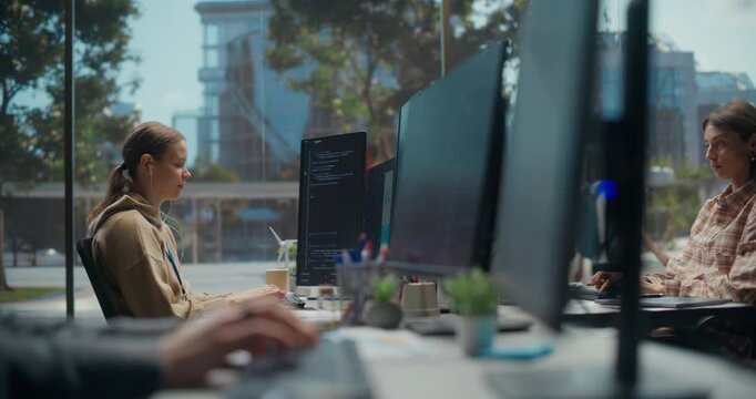 Two White Female Software Engineers Code a Cloud Based Ecommerce App on Vertical Displays in Modern Startup Office, Typing Algorithms and Testing Cybersecurity Features in Daylight Workspace.