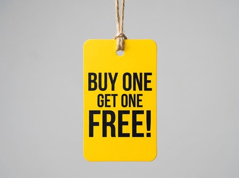 Yellow price tag with the text buy one get one free hanging on a string against a light gray background
