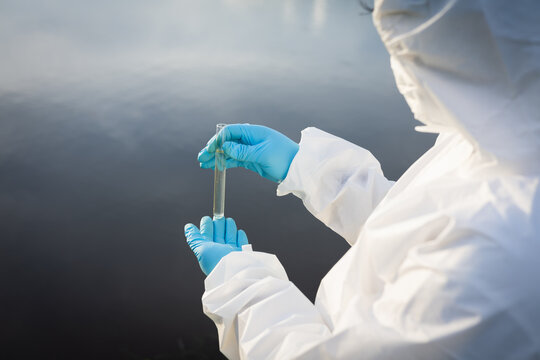 Environmental researchers in protective suit collect water samples in farmland for research and development .