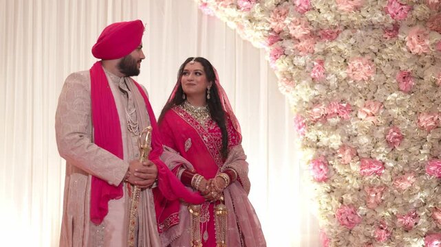Traditional Sikh Bride and Groom Standing on Reception Stage Looking at Eachother