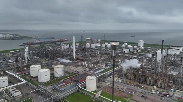 Aerial view of a chemical plant at sunset. Drone shot. Curling fire and cumin smoke filling the sky. Smoking chimneys from the factory. Chimneys of an oil refinery at sunrise pollute the environment