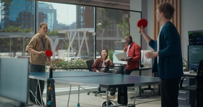 Diverse Dev Team Enjoys Play Table Tennis in Startup Office: White Woman and Man Enjoy Ping Pong While Black Engineer With Laptop and Asian Female Programmer Discuss App Code, Cybersecurity Design