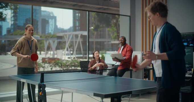 Break-time Ping Pong in a Modern Office: White Female Programmer and White Male Developer Play Table Tennis as Black Male Engineer and Asian Female Designer Watch, Cheer, Getting ready for their Game