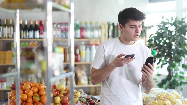 Male buyer checks suitability - scans QR code on jar of soy sauce label in a grocery store. High quality 4k footage