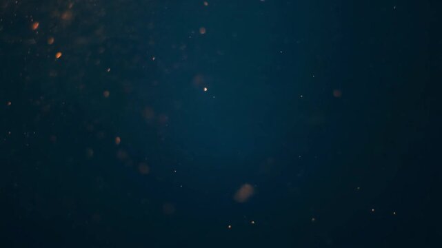 暗い深海でゆっくりと漂う光る塵や残り火のような抽象的な粒子