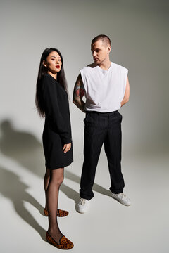 A beautiful couple dressed in trendy clothing stands close together, exuding love and style.