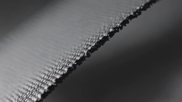 Camera shifting focus, woven band revealing serrated edge in studio macro, showing frayed fibers