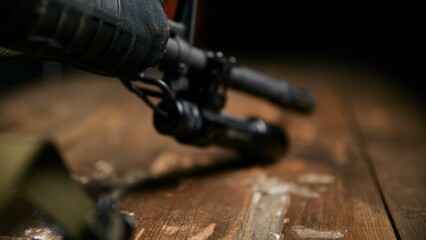 Obraz premium A low angle view of a black tactical flashlight attached to a rifle barrel housing resting on a rustic wooden table surface highlighting professional firearm illumination accessories