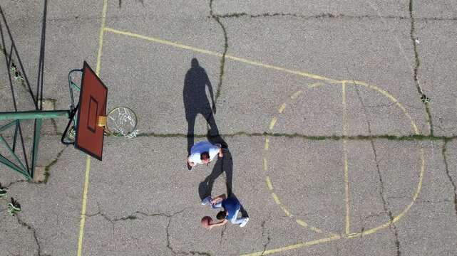 Three people playing basketball outdoors, featuring an active interaction and a thrown basketball