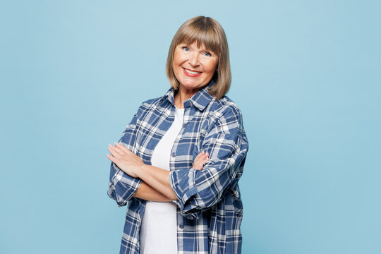 Side view elderly blonde woman 50s years old wear checkered shirt casual clothes hold hands crossed folded look camera isolated on plain pastel light blue background studio portrait Lifestyle concept