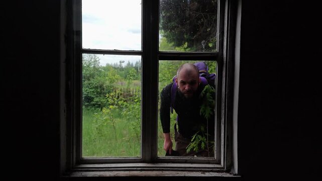 Suspicious man with a sinister expression peering through an old window close up