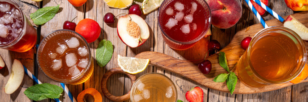 Summer refreshing drink, non alcohol tea based cocktails, iced tea varieties in different glasses, with fruit juices - strawberry, peach, apricot, cherry cold tea on wooden cozy background