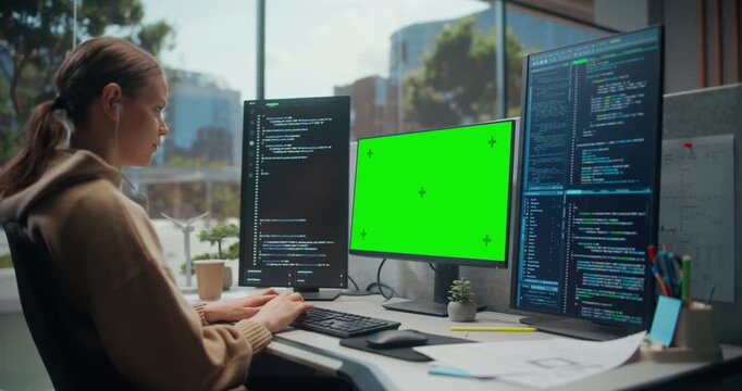 Young Woman Software Developer Typing Code in a Modern Office, Using a Chroma Key Green Screen Template for App Interface Mockup, Cybersecurity Ai Workflow and Data Dashboard Development.