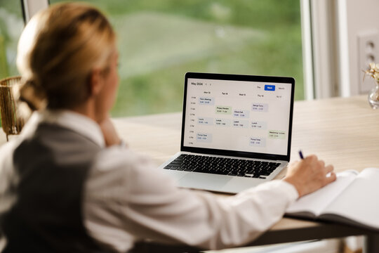 Business Professional Reviewing Weekly Schedule on Laptop at Workspace