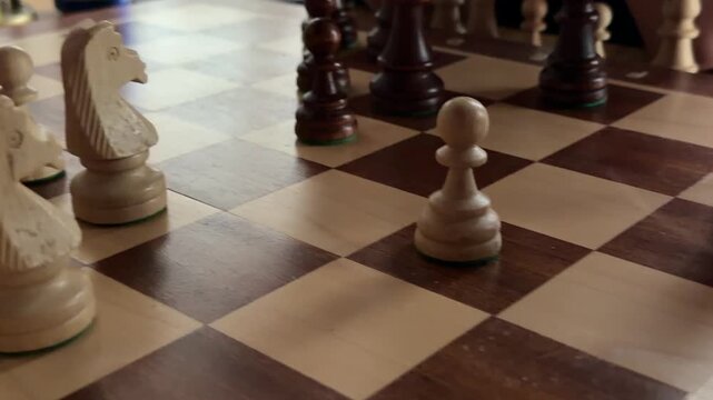 Chess pieces on board during game with black and beige figures arranged in strategic positions
