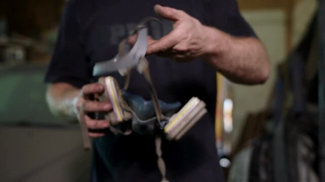 Close-up mechanic prepares pneumatic paint spray gun and angle grinder in workshop