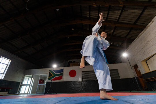 Karate practitioner performing high kick in dojo