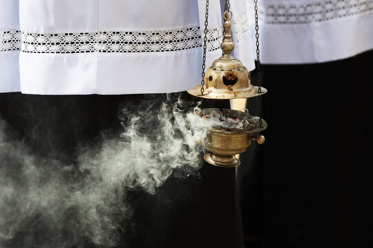 Sacristan holding thurible swinging frankincense smoke during liturgy