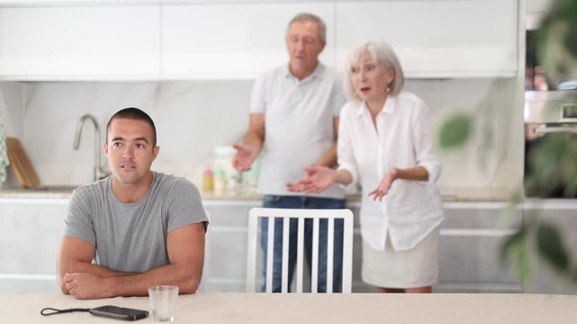 Family of threen - mother, father and son quarrel in kitchen. Eldery cuple is disappointent of adult son. High quality 4k footage