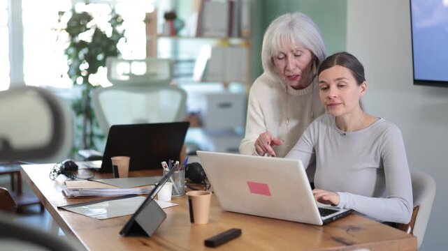 Senior female boss help to woman interns with laptop task. High quality 4k footage