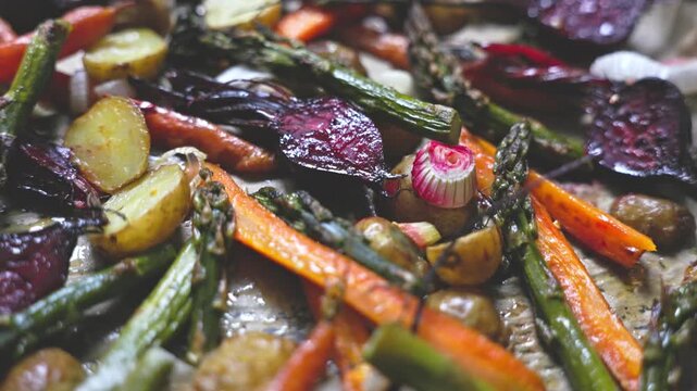 Close-up video of delicious organic vegan food. Oven-baked asparagus, carrots, and beetroots with garlic and herbs. Concept of clean eating, nutrition, and wholesome culinary lifestyle.
