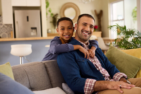 Happy and smiling black boy embracing from behind his father