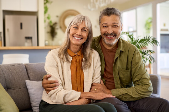 Senior multiethnic retired couple hugging and looking at camera at home