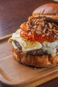 close up of flamed brie cheese on top of hamburger with pepper jelly and crispy onion