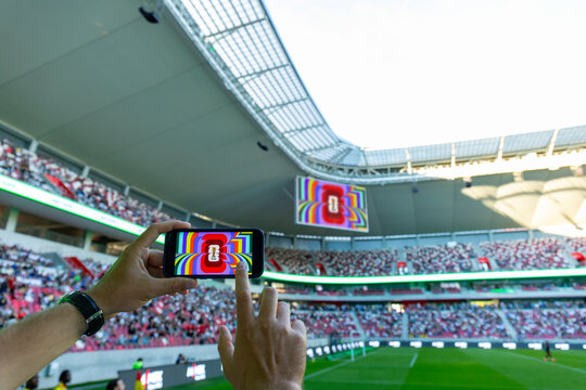 MINSK, BELARUS JUNE 9, 2026: Man holding a purple Apple iPhone 14 Pro in the stadium. The official logo of the football World Cup in the USA, Mexico, and Canada.