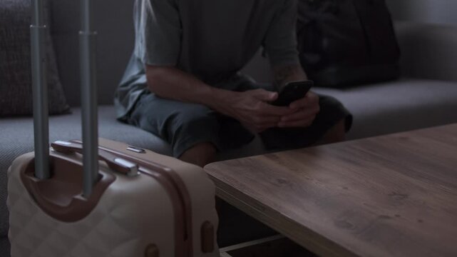Digital nomad using smartphone to arrange travel plans in temporary apartment, booking accommodation or transportation for next destination