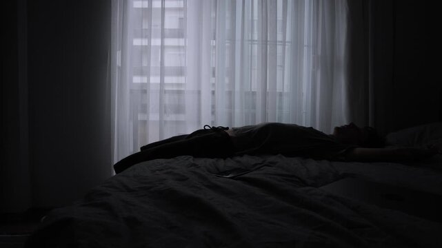 Depressed man with head down sitting on bed in despair in home office next laptop, illustrating mental fatigue. Realistic depiction of freelance burnout.