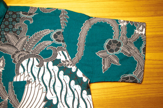 Close-up of the short sleeve and shoulder seam details of a men's traditional Indonesian batik shirt with green turquoise floral and parang motifs