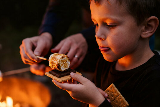 Little Boy Making Smores with Marshmallow and Chocolate by Campfire