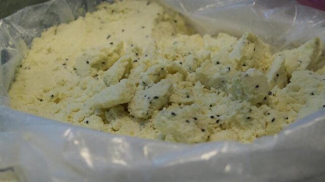 Traditional Turkish market crumbly cheese texture close up with black cumin seeds in bag, artisanal dairy product concept, healthy organic food detail