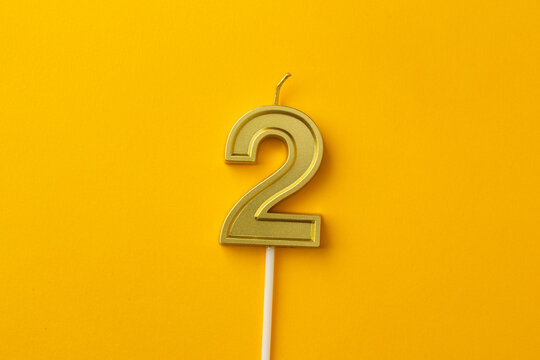 Gold Number 2 Birthday Candle on Bright Yellow Background