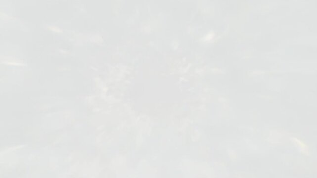 Zooming camera focusing on circular bright light at dark ceiling, revealing halo and overexposure