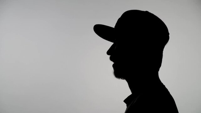 An anonymous silhouette of a man in a cap gives an interview and tells something excitedly