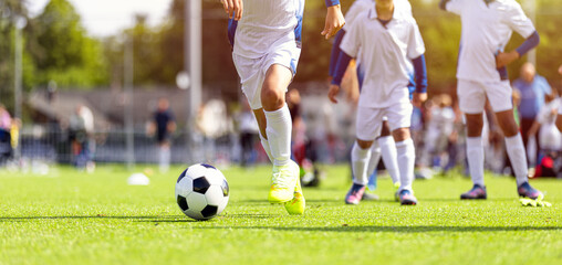 Naklejka premium Youth Soccer Action Shot: Close-Up of Kids Running and Dribbling Ball on Green Pitch