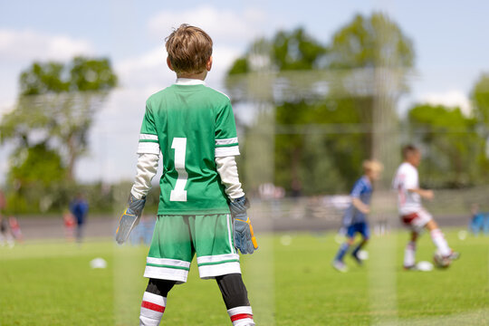 Young Soccer Goalkeeper: Kid in Green Jersey Number 1 Watching Football Match