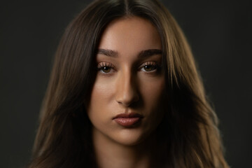Naklejka premium Young woman posing in a studio closeup, looking directly at camera with intense expression