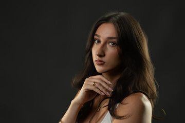 Fototapeta premium Beautiful young woman with dark hair posing in a studio for a beauty portrait
