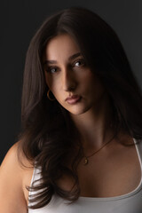 Fototapeta premium Young woman posing with elegant makeup and long dark hair in a studio portrait