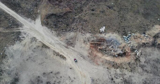 Aerial View of ATV quad bike rider drive fast on rural mountain dirt road trail
