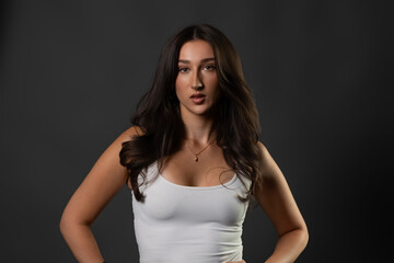 Fototapeta premium Confident brunette model wearing a white tank top posing for beauty and fashion concepts