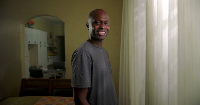 African American man standing by window at home smiling calmly, relaxed mood, everyday domestic moment, quiet confidence, natural human presence