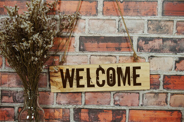 Fototapeta premium Wooden Welcome sign hanging on old brick wall background