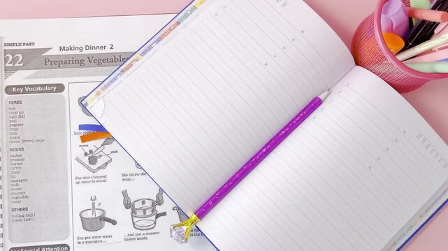 English textbook and notebook on a pink desk. Studying vocabulary about cooking and preparing vegetables for a school lesson, with a purple pencil and a pen holder