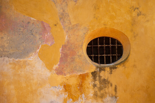Round opening with a metal grate in the wall in the Palace of the Inquisition, in Cartagena, Colombia
