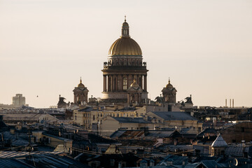 Fototapeta premium Majestic golden dome of a grand cathedral towering over a dense layer of old city rooftops at sunset.